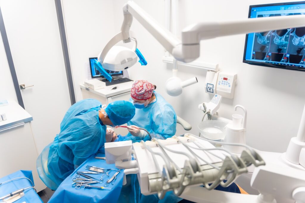 Dental clinic, dentists in blue suits performing an operation on an implant