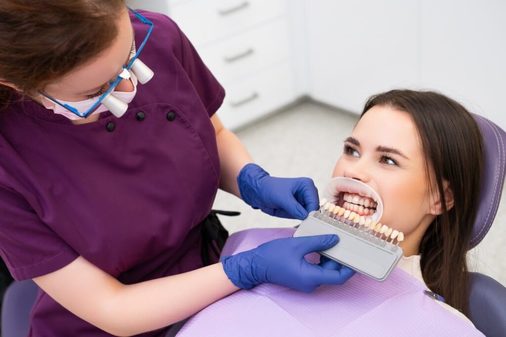 Dentist matching the shades of the implants for teeth whitening for the patient